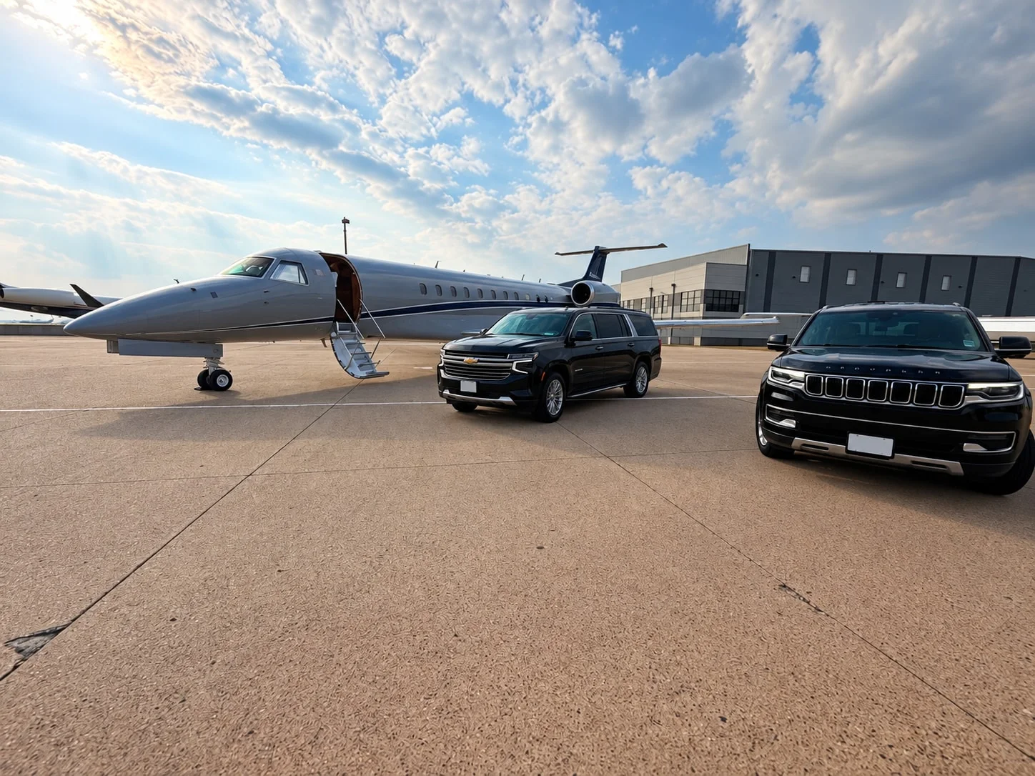 Two black SUVs parked beside a private jet on an airport apron.