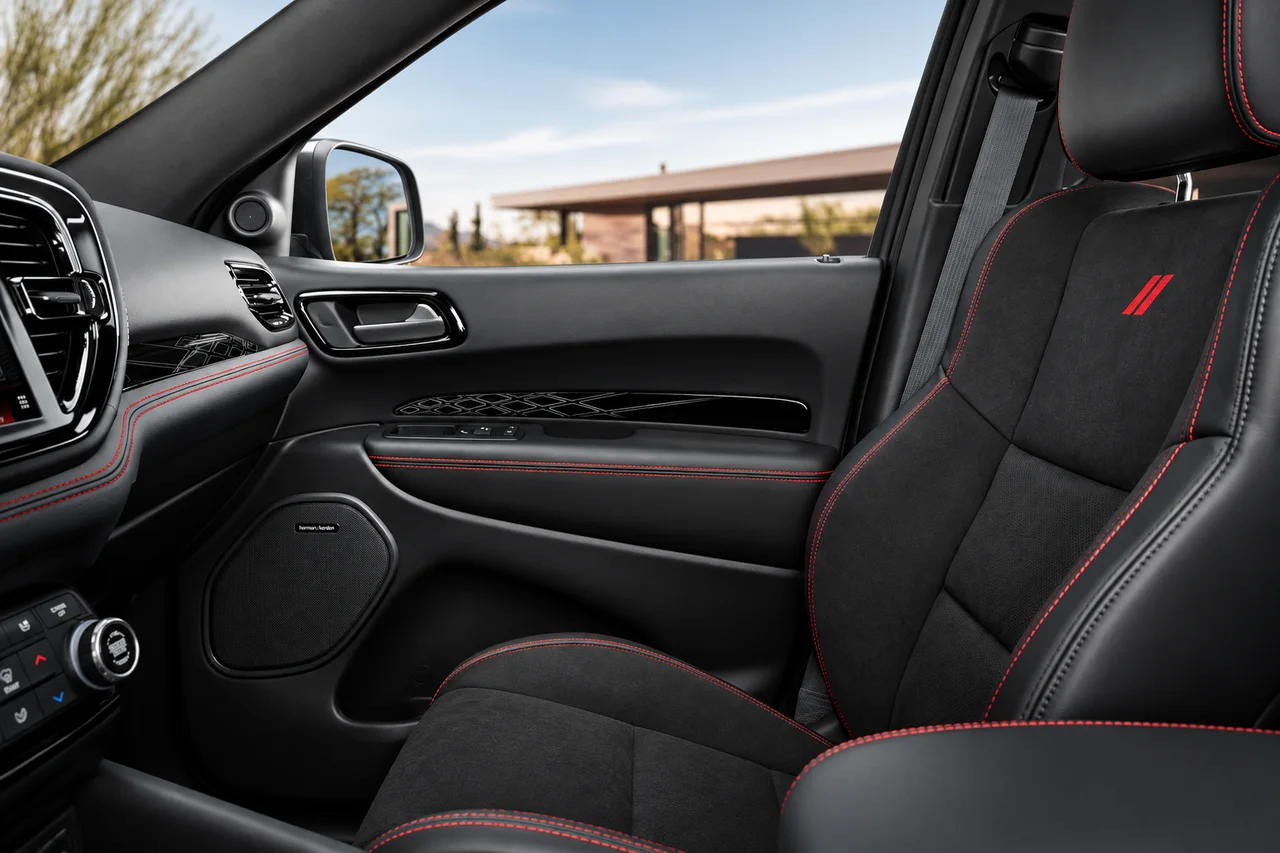 AI-recreated Dodge Durango passenger seat with black upholstery, red stitching and factory double-slash emblem beside the passenger door.