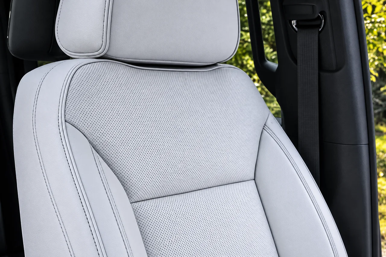 AI-enhanced detail reference of a light gray perforated Suburban seat with stitched bolsters and a headrest beside a black seat belt.